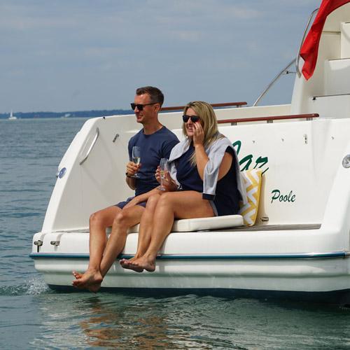 man and woman sat on the edge of a yacht